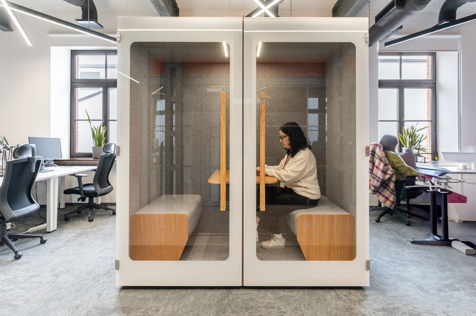 Cabine acoustique NINA 2 installée en open-space d'entreprise moderne, utilisatrice en visioconférence