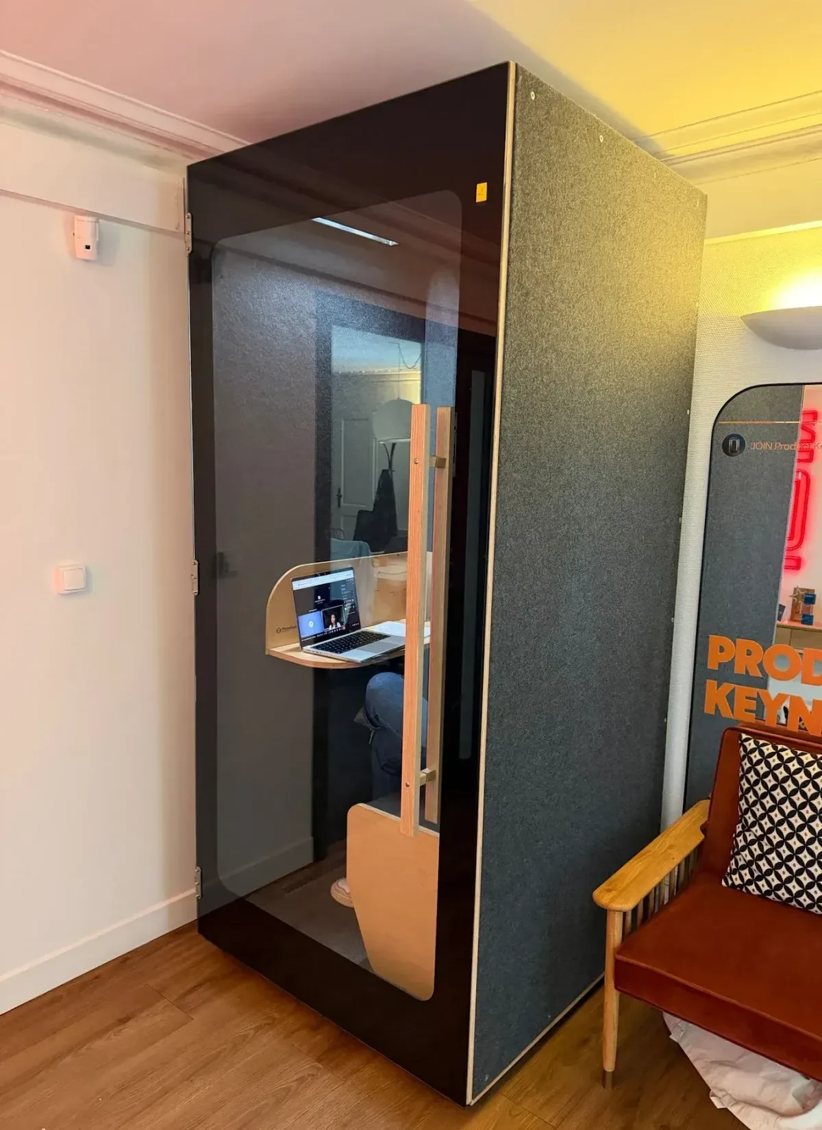 Cabine acoustique NINA noire installée en bureau parisien — utilisateur travaillant à l'intérieur